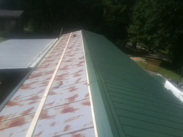 Old rusted panels beside newly installed green metal roofing — Wind Damage Roof Repair by Roofing Brothers in Sarasota