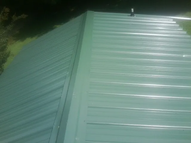 New green metal panels meeting at the ridge of a roof — Flat Roof Repair work by our crew in Sarasota
