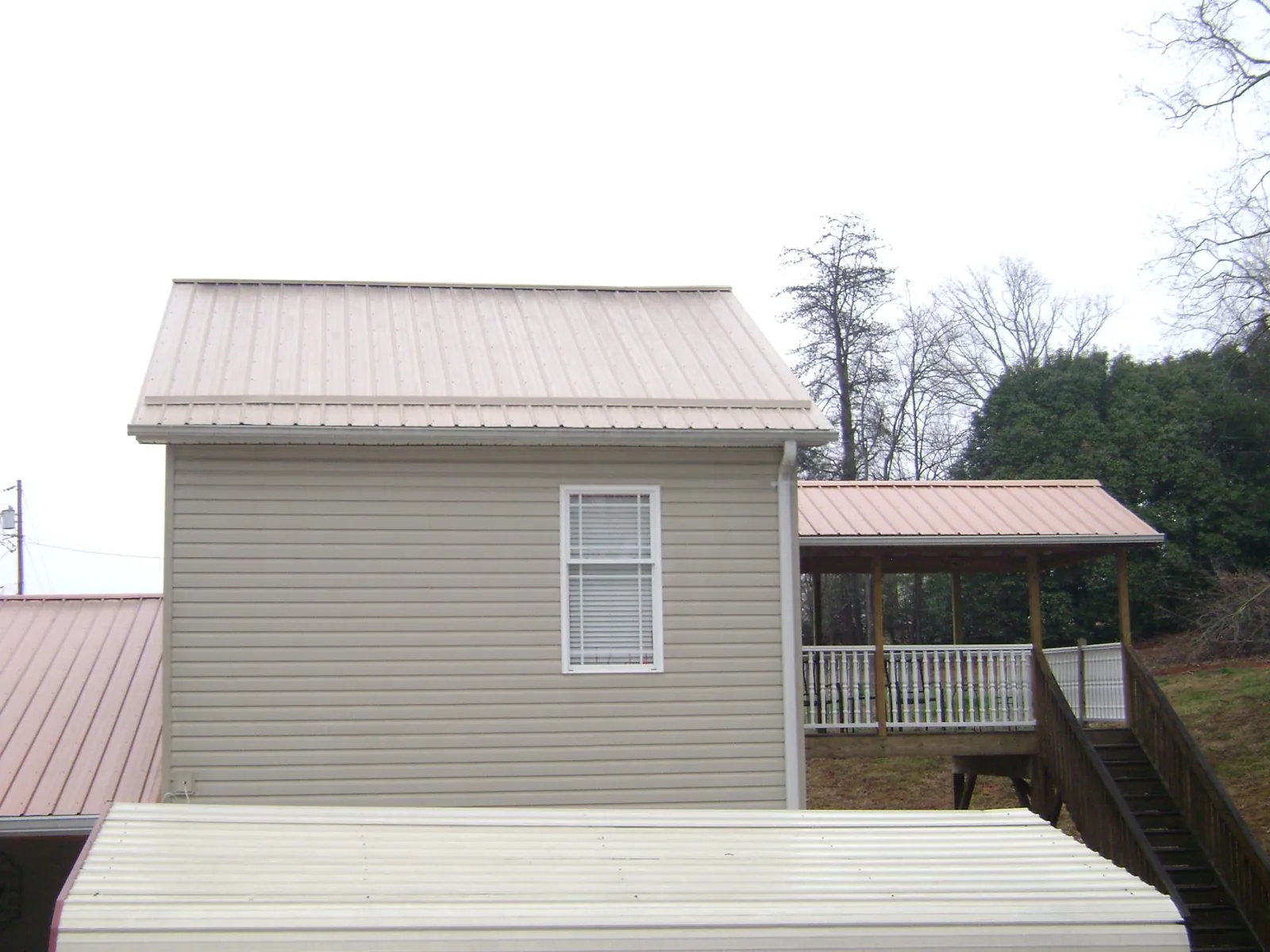 Tan metal roofs on a two story addition and attached porch, from a Roof Replacement job in Sarasota