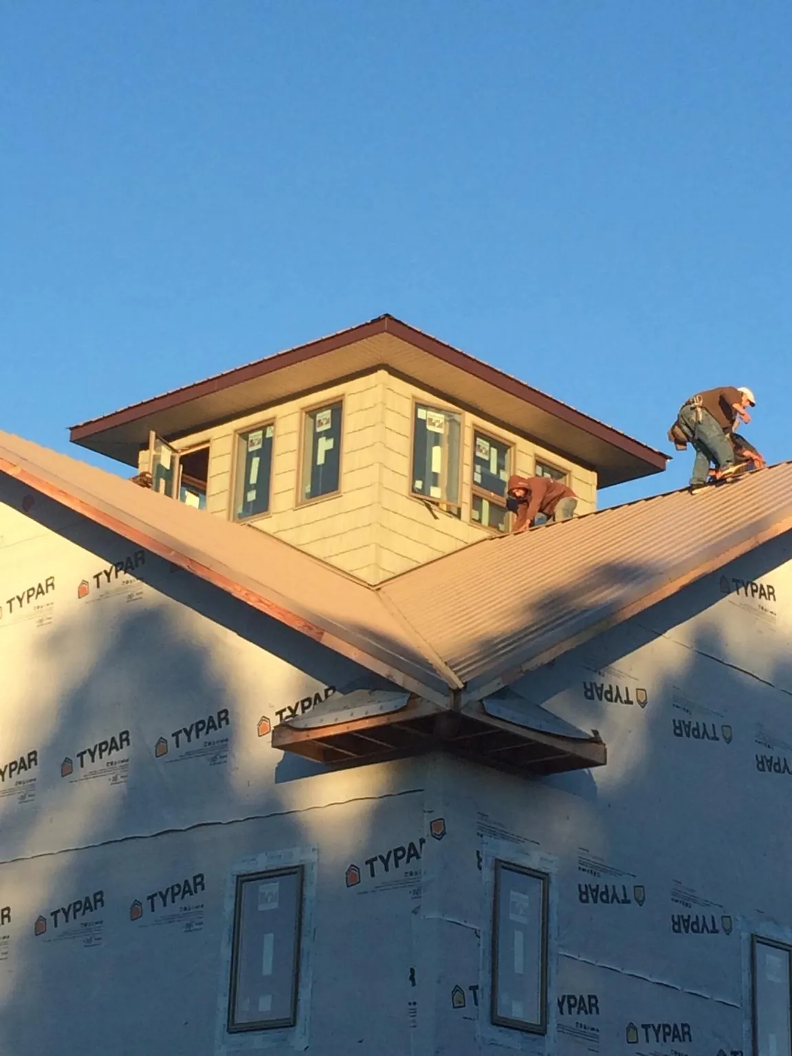 Roofers working around a rooftop cupola on a new metal roof at sunset — Roof Waterproofing in Sarasota by Roofing Brothers